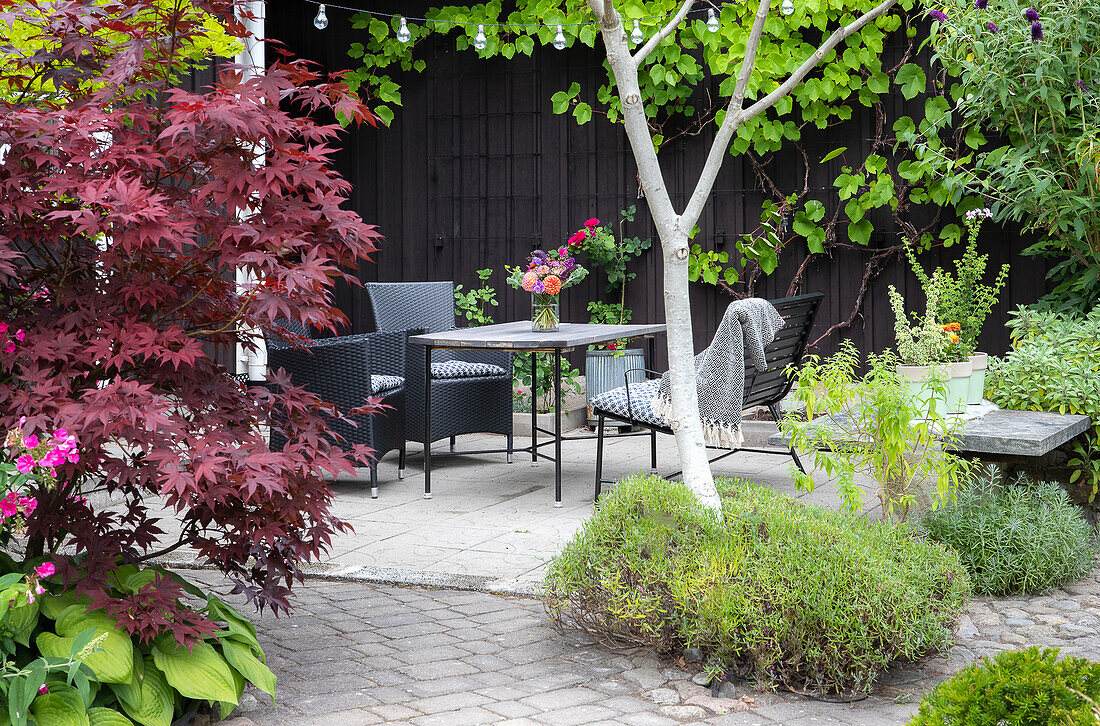 Terrassensitzgruppe umgeben von vielfältiger Bepflanzung im Garten