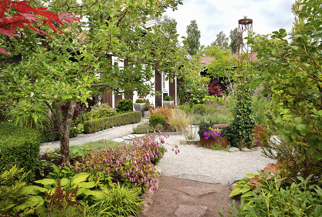 Well-tended front garden with gravel path and diverse plantings in front of a house