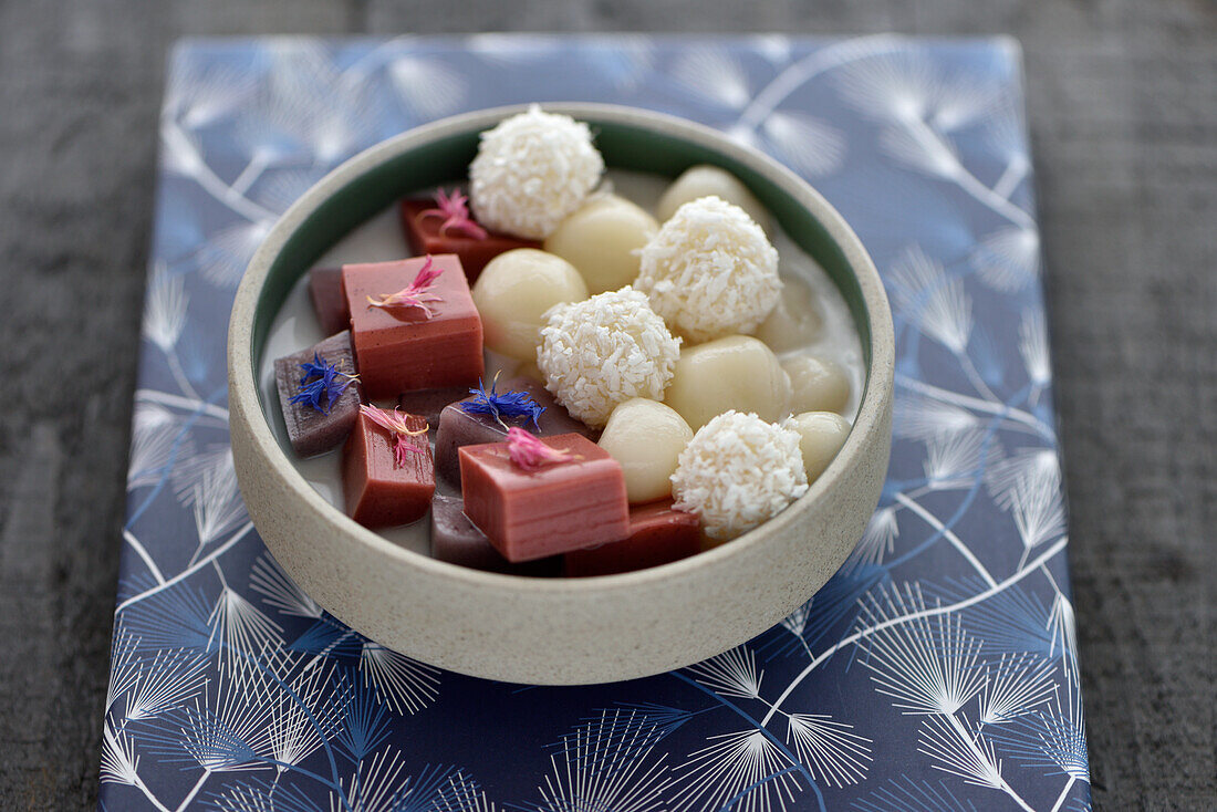 Vegan sweet sticky rice balls with blueberry and strawberry pannacotta cubes and coconut milk
