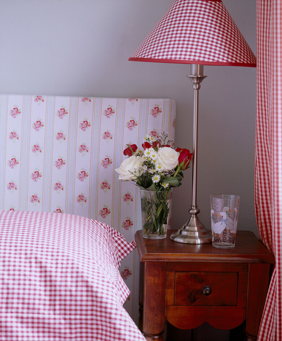 Bett mit gepolstertem Kopfteil und Lampe mit Lampenschirm im Gingham-Muster