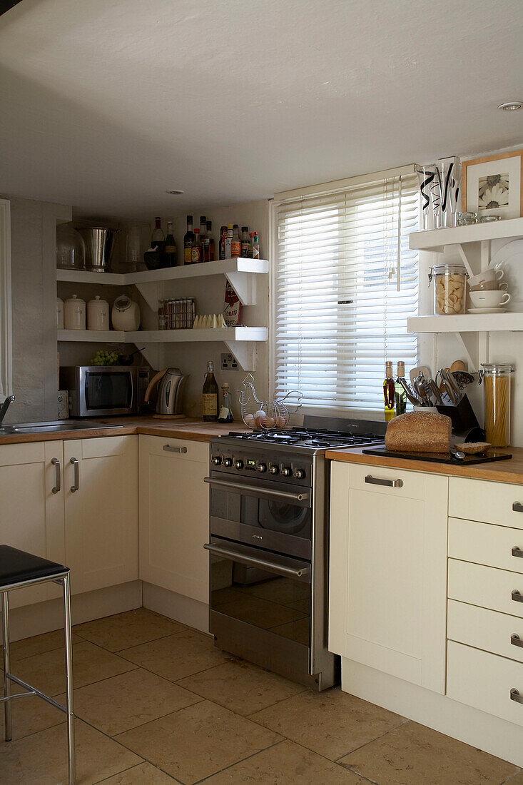 Stainless steel oven under window in cream kitchen