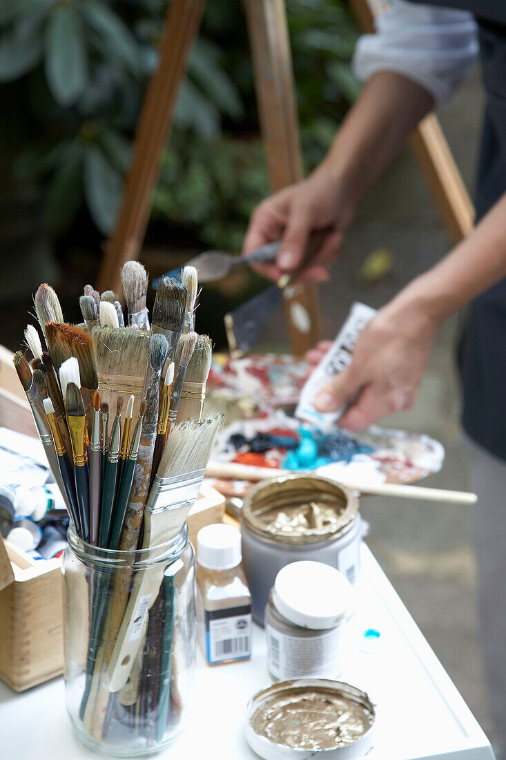 Künstlerin mischt Farben mit Pinseln auf Palette