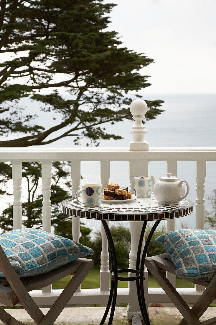 Table and chair with cushions on balcony of Devon home