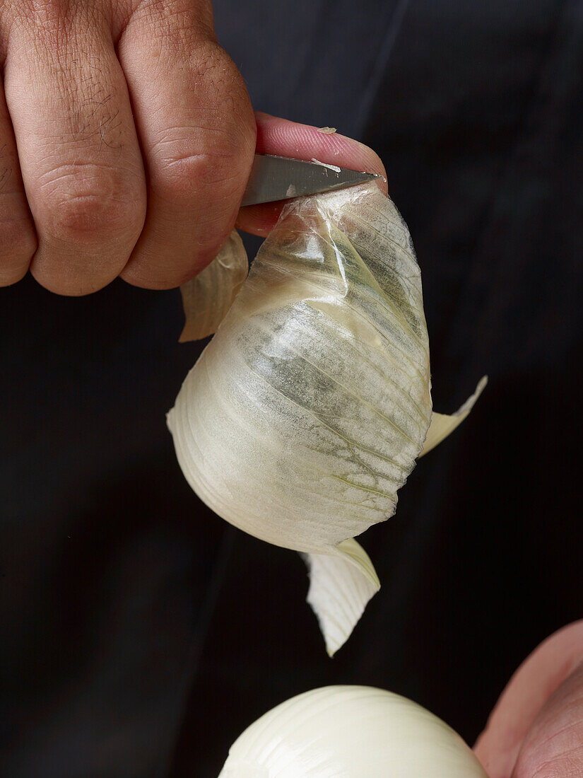 Peeling a white onion (close-up)