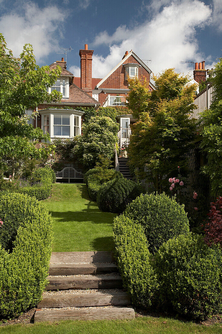Brick house exterior and sloping garden lawn in Arundel, West Sussex