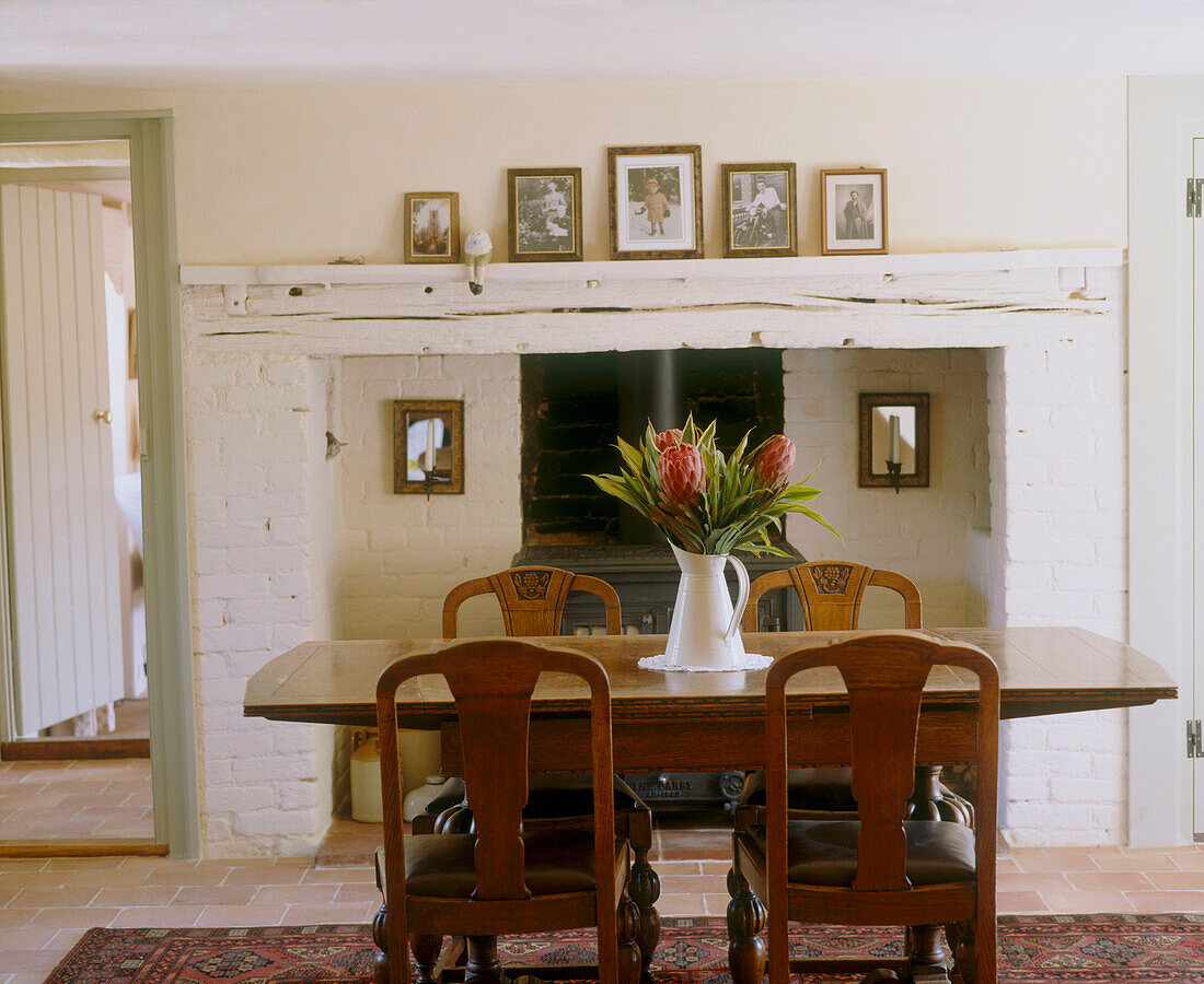 Rustic wooden dining table with vase of flowers fireplace in a country style room