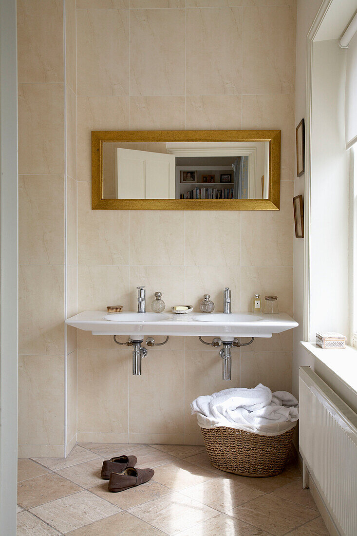 Mirror above double basin with laundry basket in Arundel bathroom, West Sussex