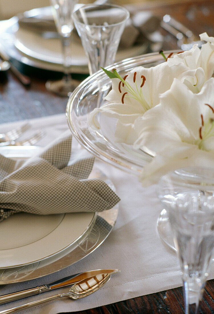 Close up detail a place setting with flowers in a glass vase