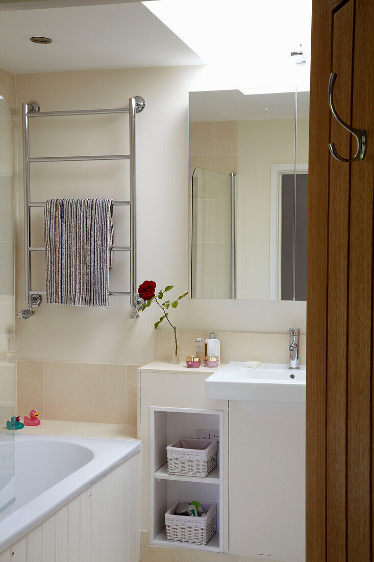 Under sink storage and heated towel rail in cream coloured bathroom