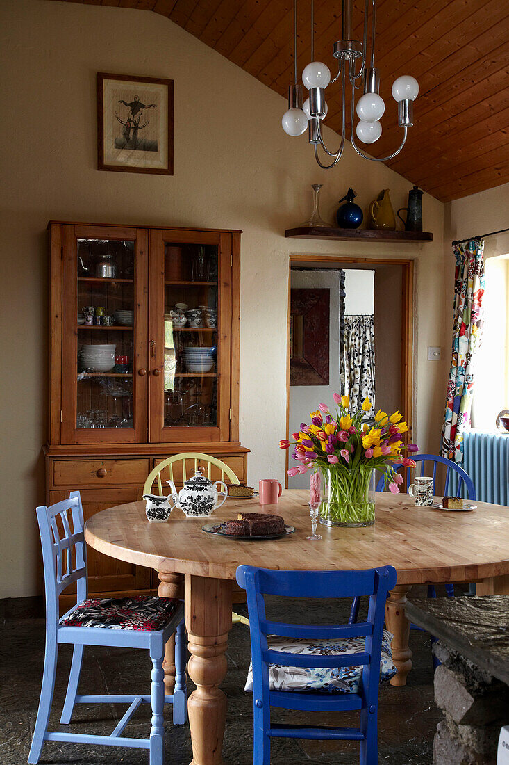 Wooden kitchen dresser and table with mismatched chairs