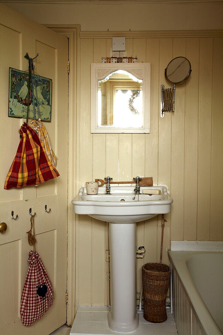 Checked wash bags hang on back of bathroom door in Brighton home, UK