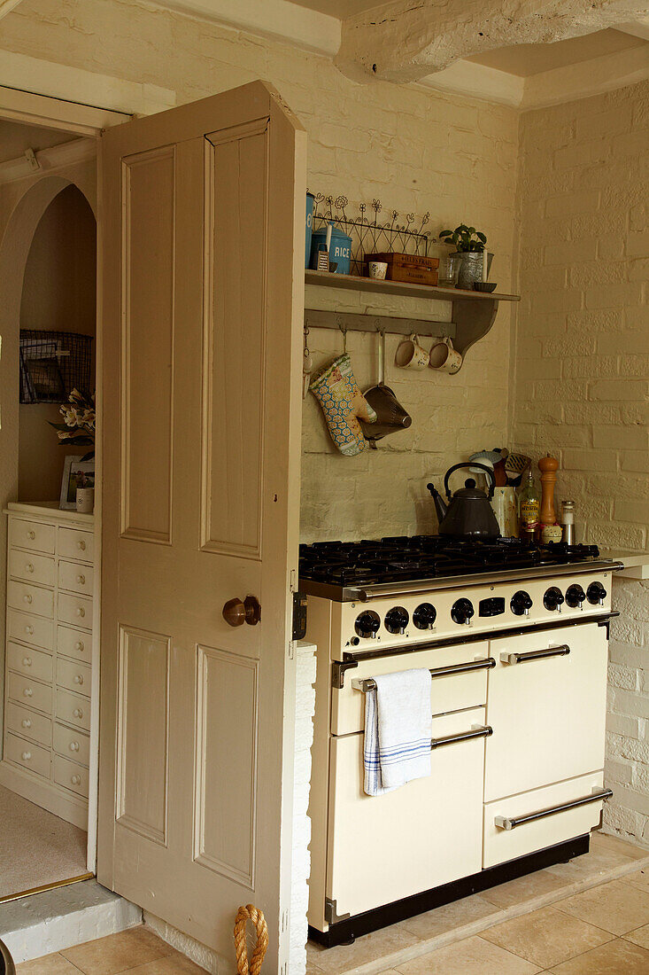 Cream Aga behind open door in kitchen of West Sussex home, England, UK