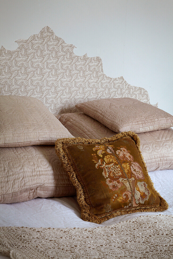 Gold covered cushion and quilted pillows on bed of London home