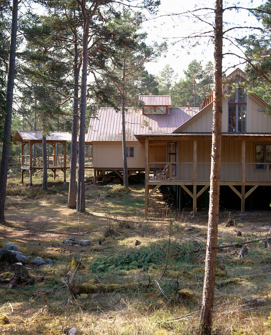 Exterior view of a traditional wooden house raised on wooden legs surrounded by trees