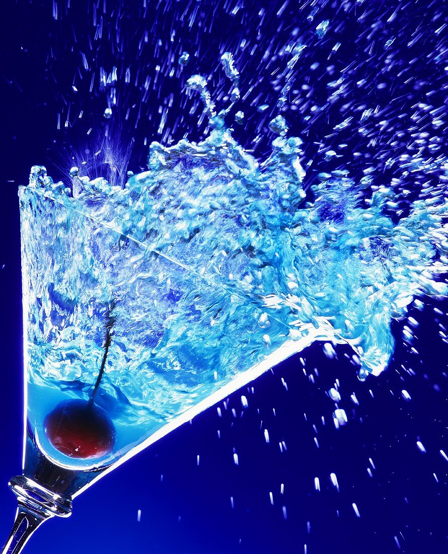 Blue Curacao cocktail spilling out of Martini glass