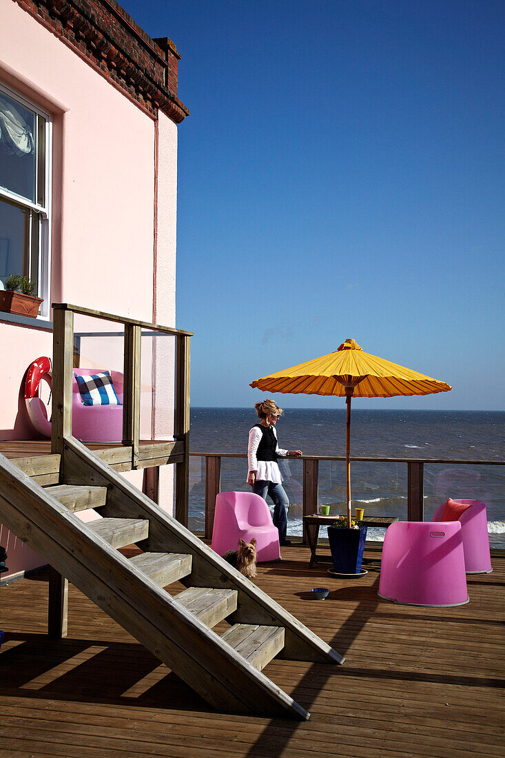 Woman on balcony terrace of Cromer beach house in Norfolk, UK