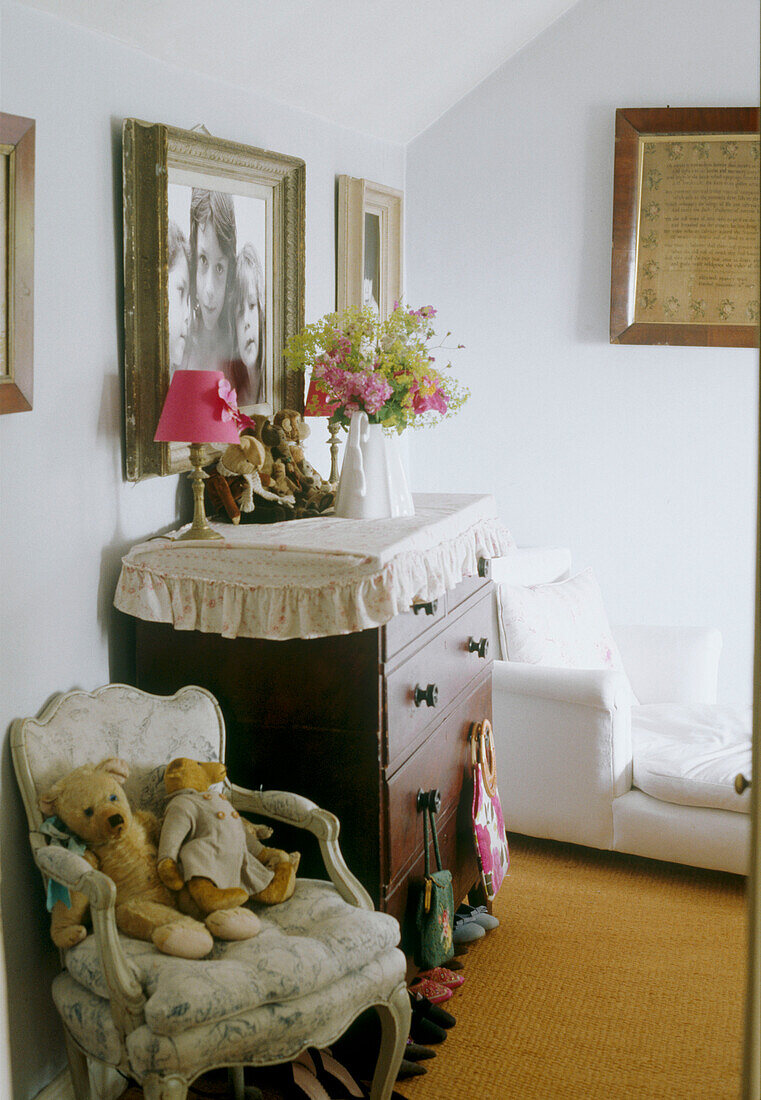 Flower and lamp on chest of drawers in traditional style bedroom