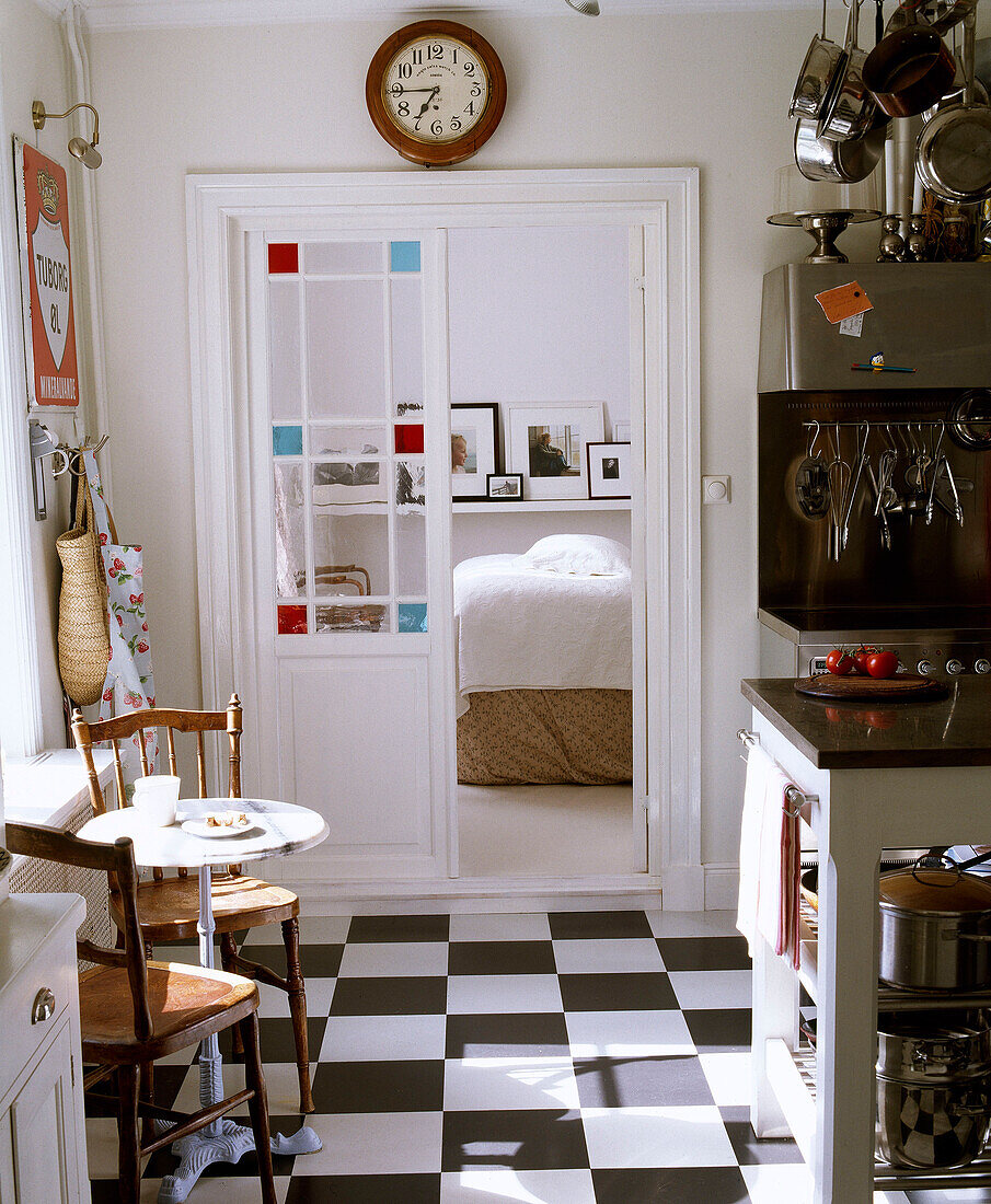 Frühstückstisch und Holzstühle in einer Küche im Landhausstil mit Blick auf den dahinter liegenden Raum