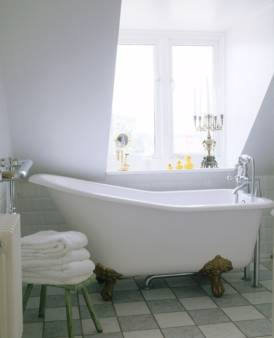13535444 A Traditional Bathroom Freestanding Bathtub Below A Sloping Ceiling With A Large Window And A Tiled Floor 