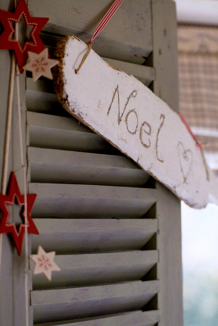 Close up detail of hand carved sign saying Ã¯0el' hanging from a shutter door