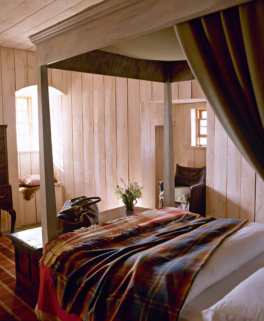 Four poster bed in wooden panelled bedroom