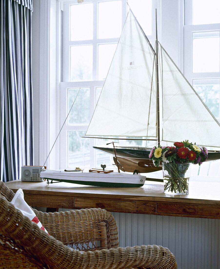 Wicker chair in front of window sill with model boat