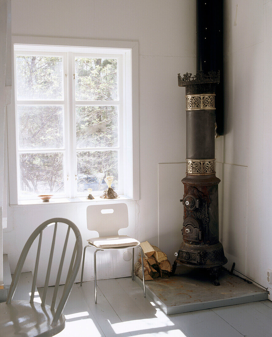 Wood burning stove in the corner of a room with white walls and furniture