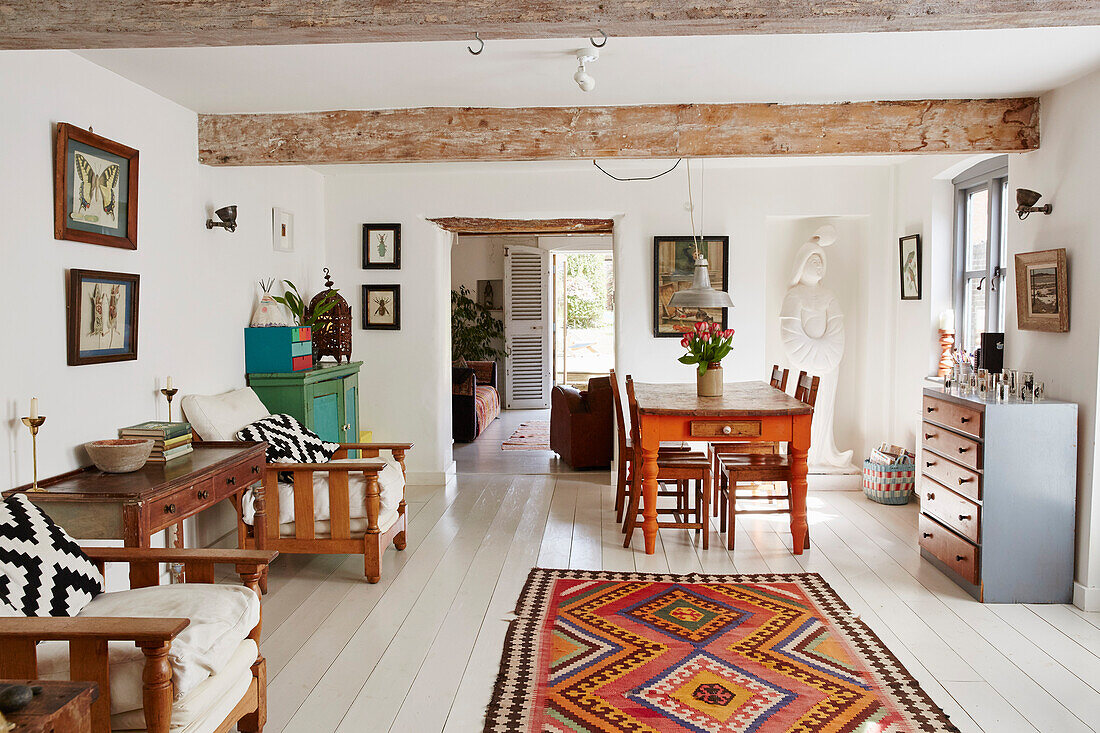 Holzmöbel in einem offenen Wohnzimmer mit weiß gestrichenen Dielen in einem Haus in Bridport, Dorset, Großbritannien