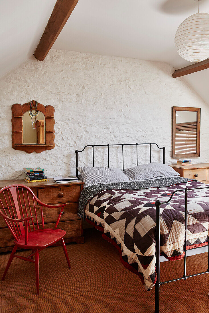 Patchwork quilt on metal framed bed in whitewashed Bridport home, Dorset, UK