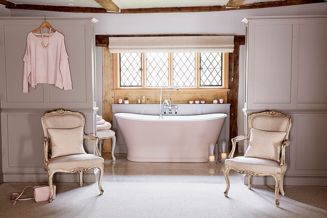 Antique chairs at entrance to open plan en suite bathroom in restored Grade II listed farmhouse Kent, UK