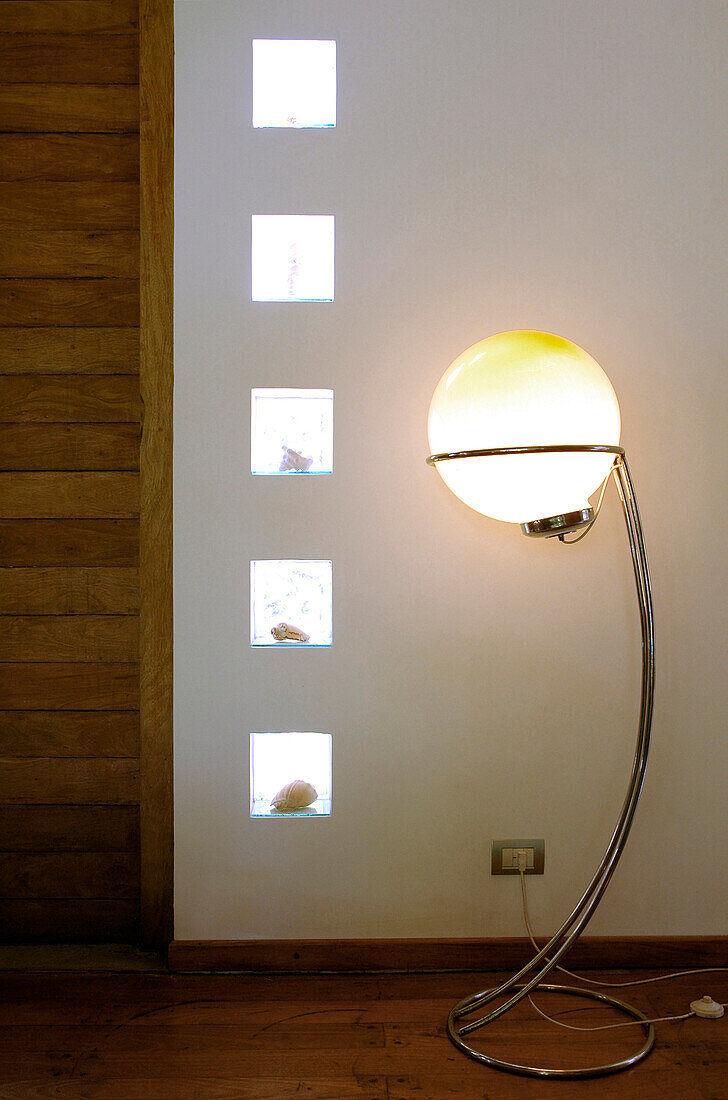 Living-room with glass bricks embedded with seashells and lit orb standard lamp