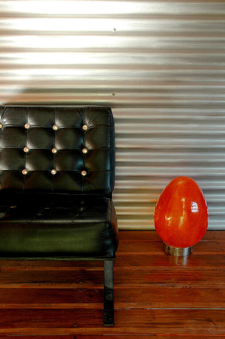 Metal sheeting on walls of entrance hall contrast with a wooden floor laid as a deck with gaps between the boards