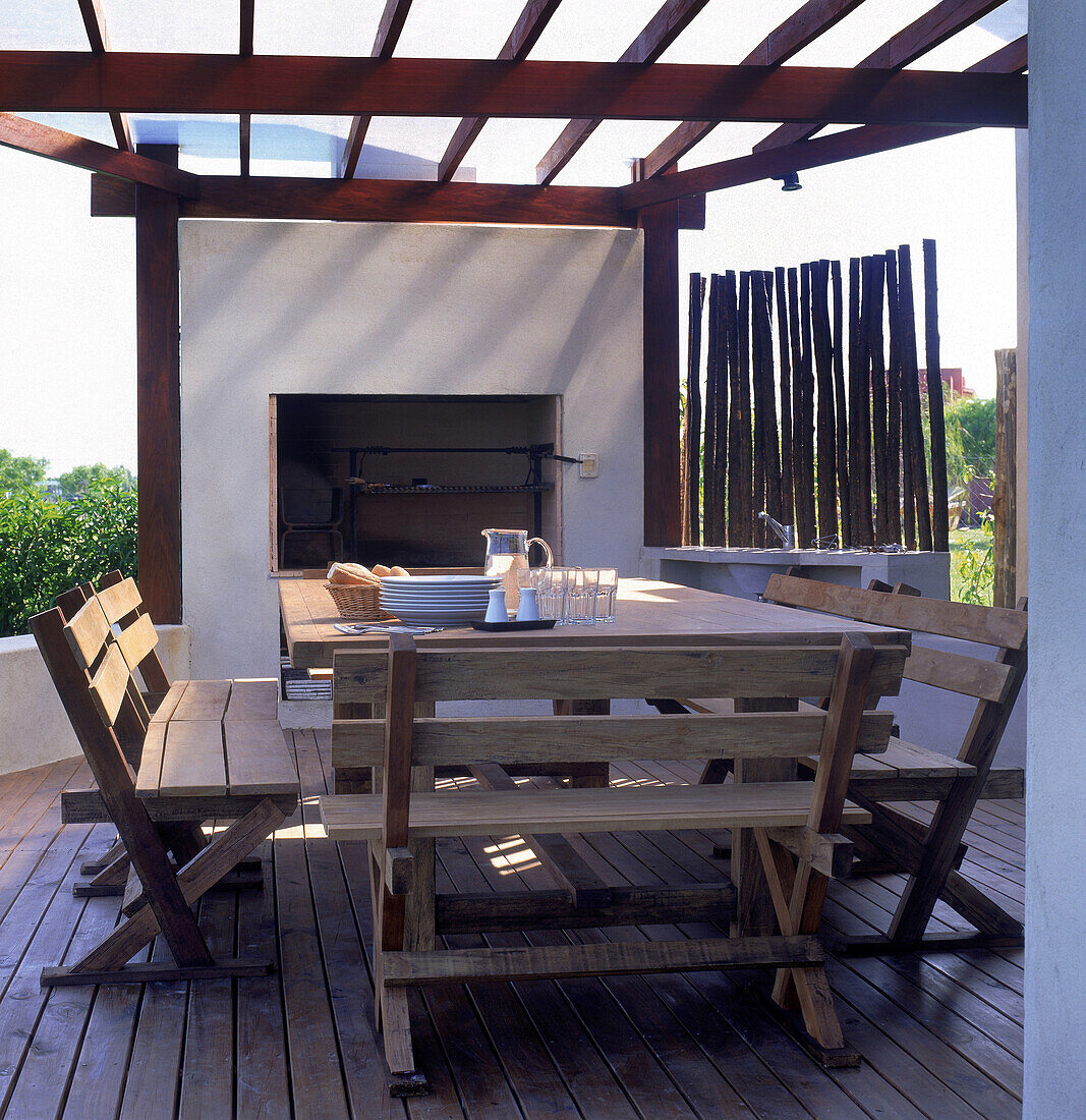 Grillplatz mit Sitzbänken und einer Wand aus vertikal aufgestellten Holzscheiten