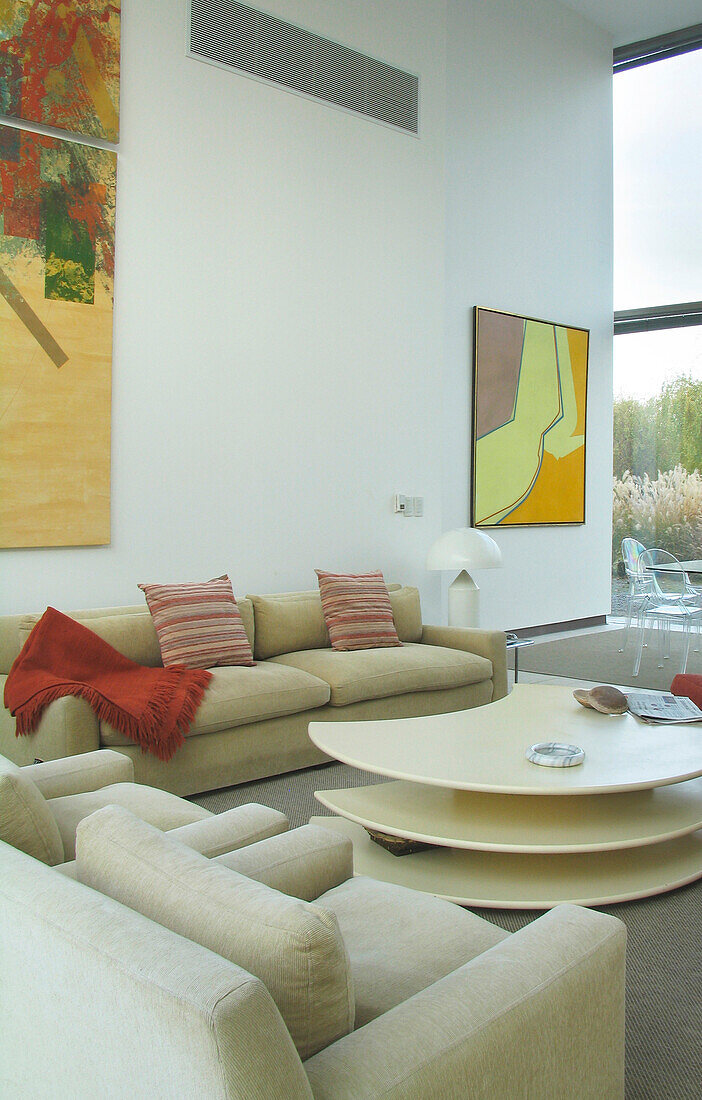 Seating area with sofa upholstered with neutral fabric and artwork by Alberto Carbi
