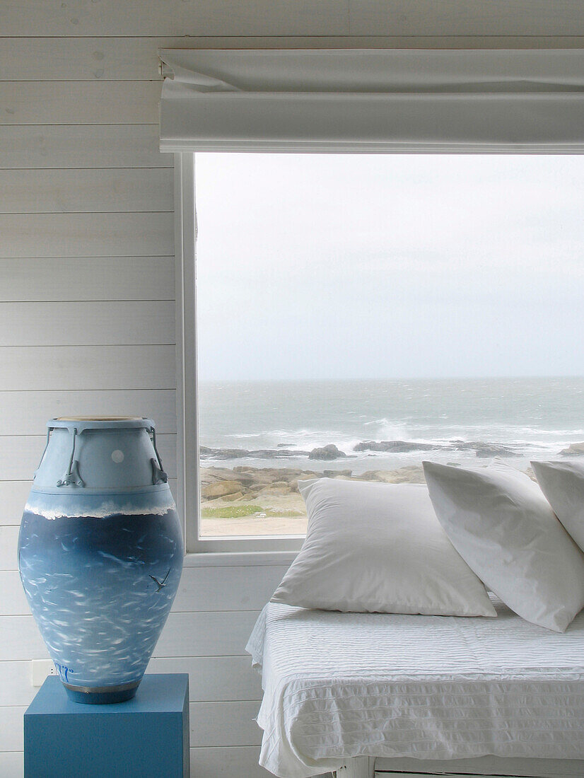 Blue painted drum beside daybed under beach house window