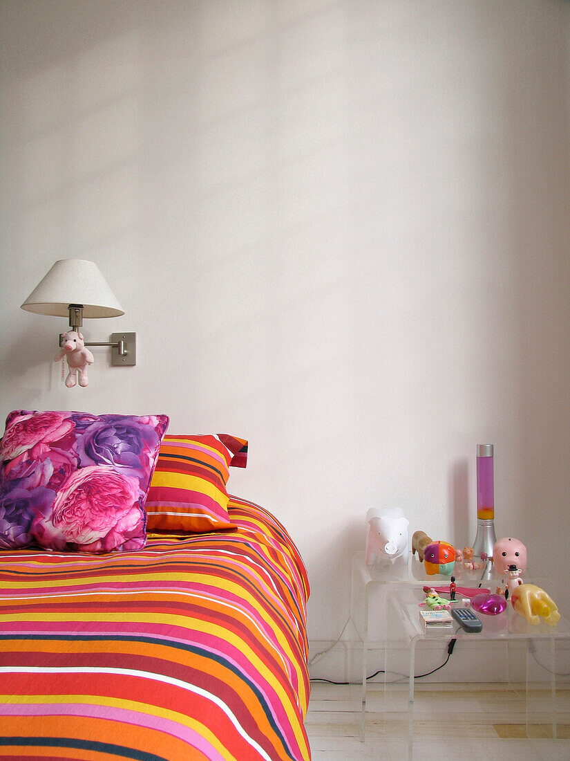 Striped bed cover on single bed with Perspex bedside table