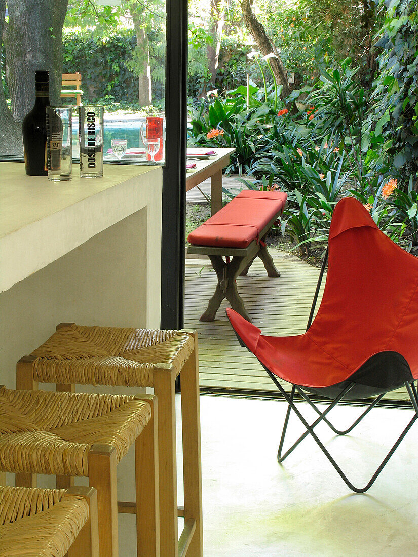 Roter Klappstuhl auf einer Gartenterrasse, die sich vom Barbereich aus öffnet