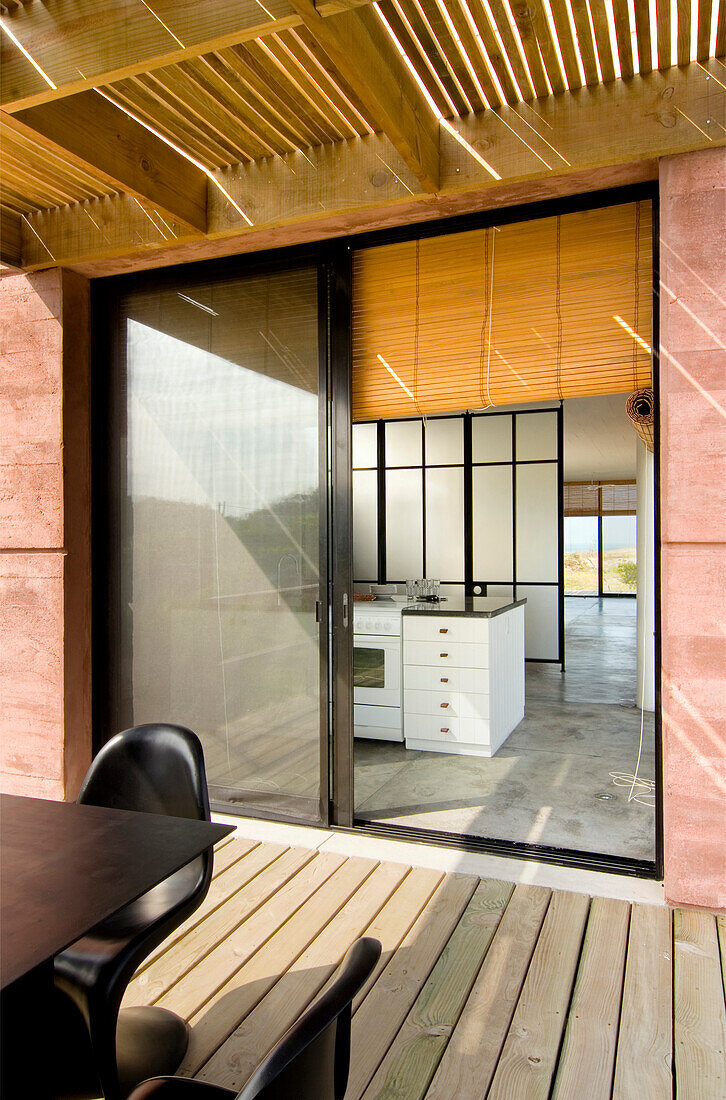View through sliding doors to summerhouse interior with concrete floors and Japanese folding screen