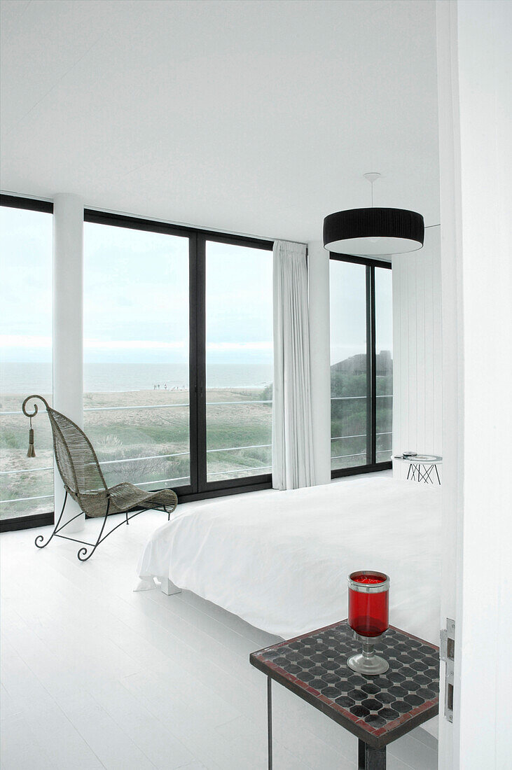 White bedroom interior with large windows and view to sea