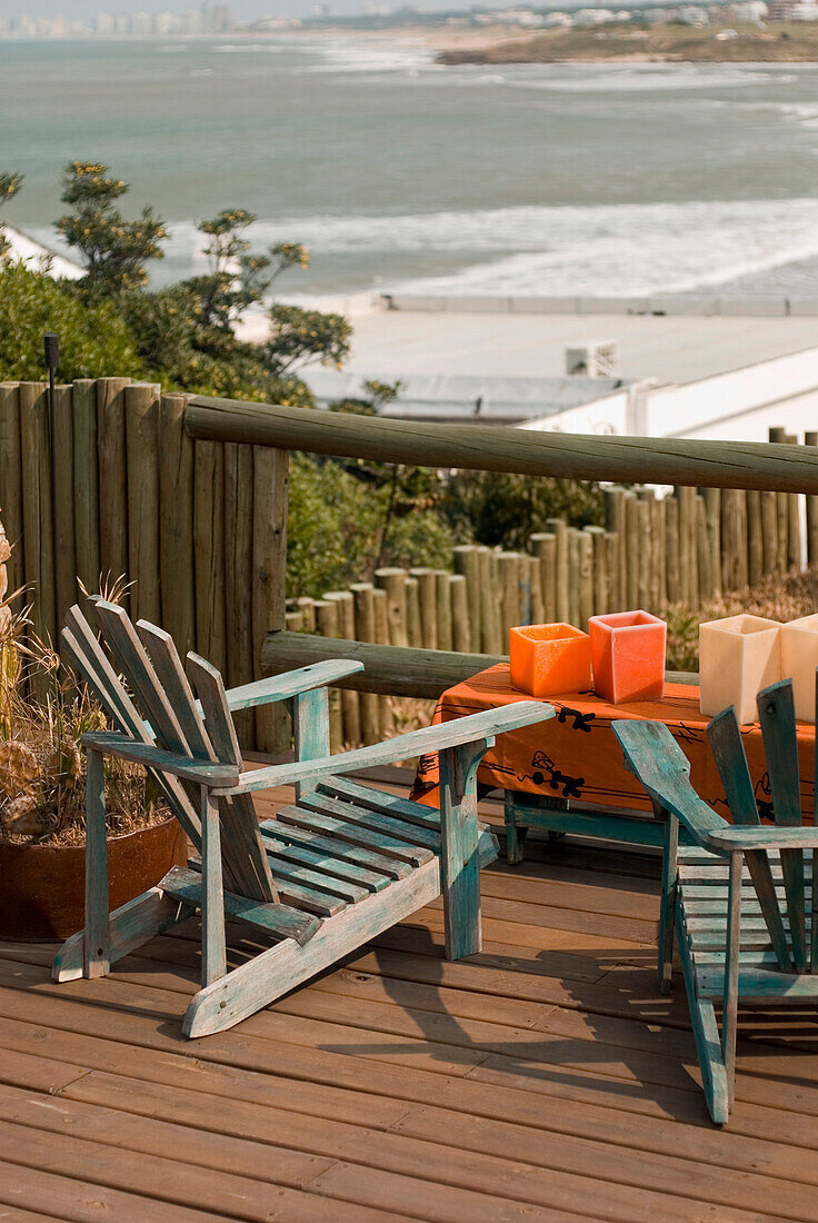 Wooden armchairs on roof terrace with view to sea