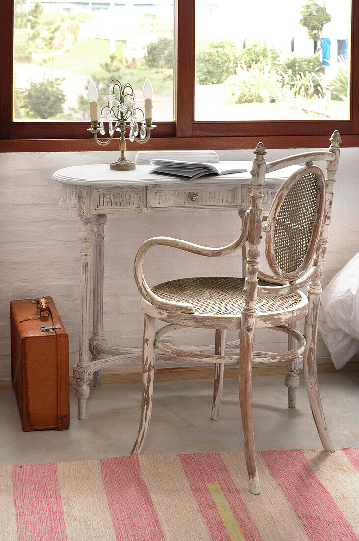 Salvaged chair at desk with briefcase below window