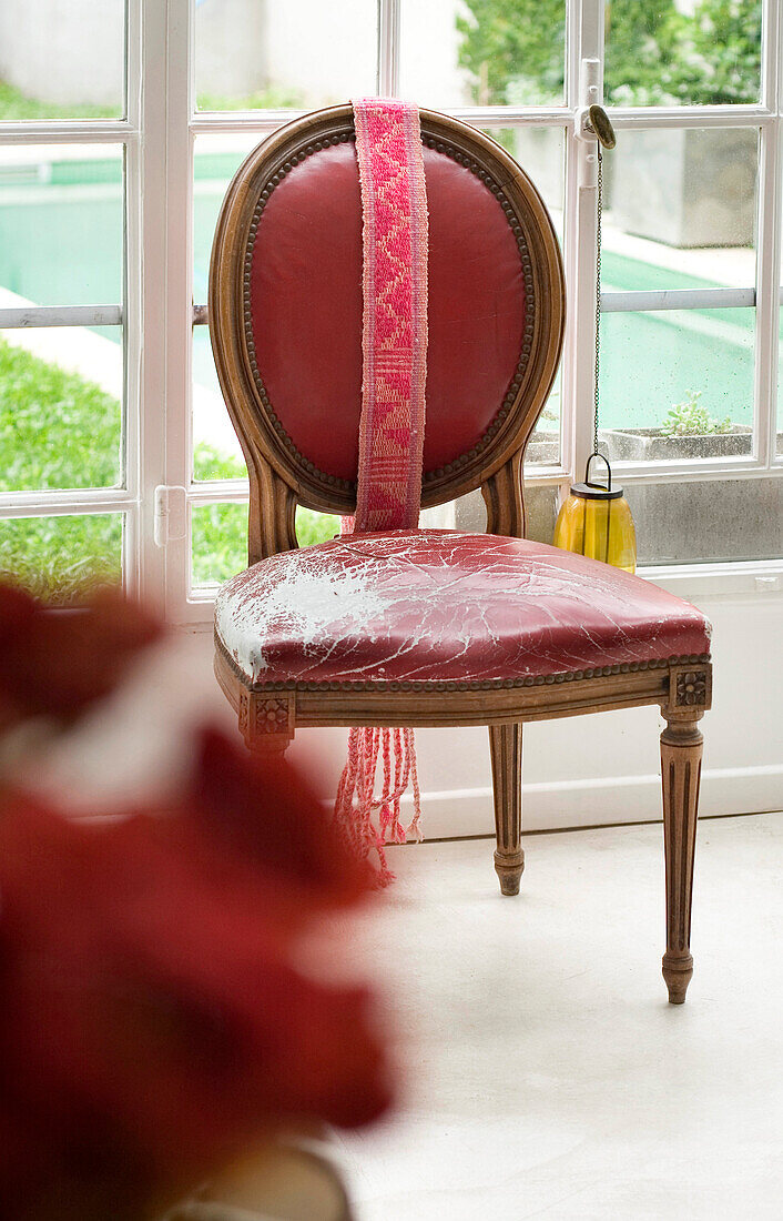 Wohnzimmer mit Tagesbett unter der Treppe, antike Kommode und Blick durch ein großes Fenster in den Garten