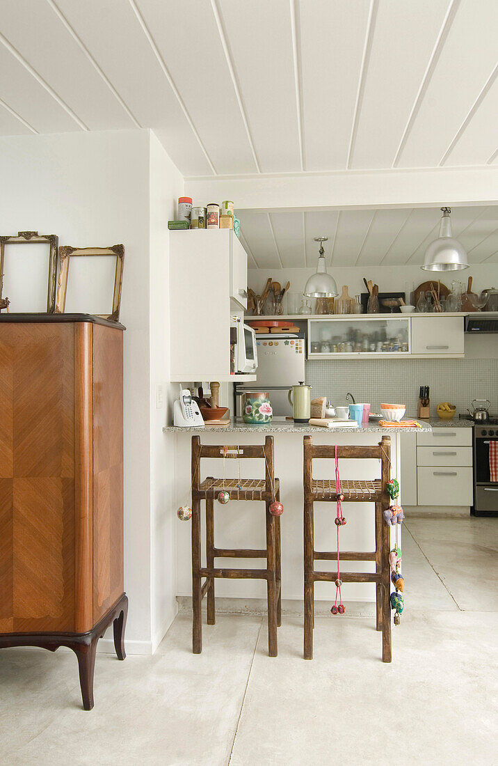 White kitchen with panelled ceiling barstools and antique dresser