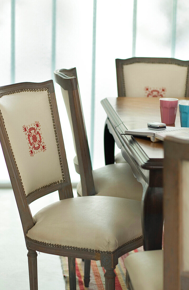 Embroidered detail on dining chair at table with notebook