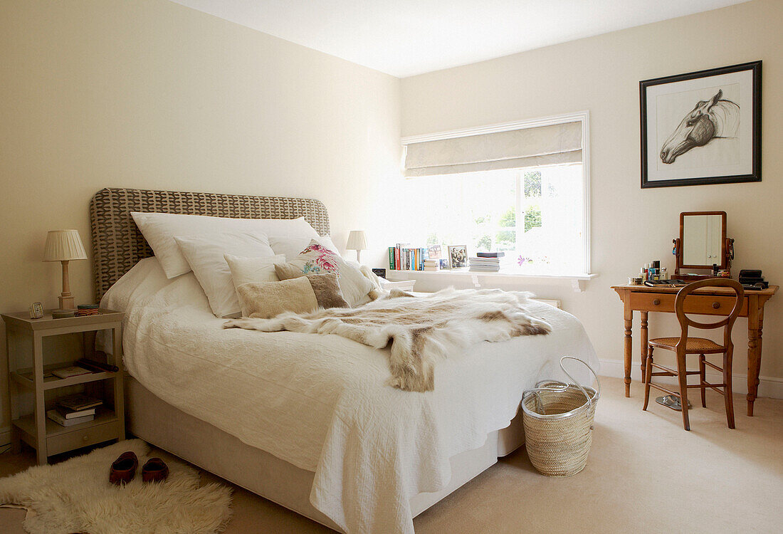 Double bed with white bedspread and fur throw with rug in17th Century Oxfordshire bedroom