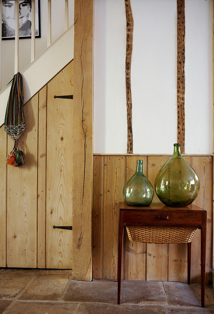 Two green glass vases on wooden coffee table with panelled under stairs storage