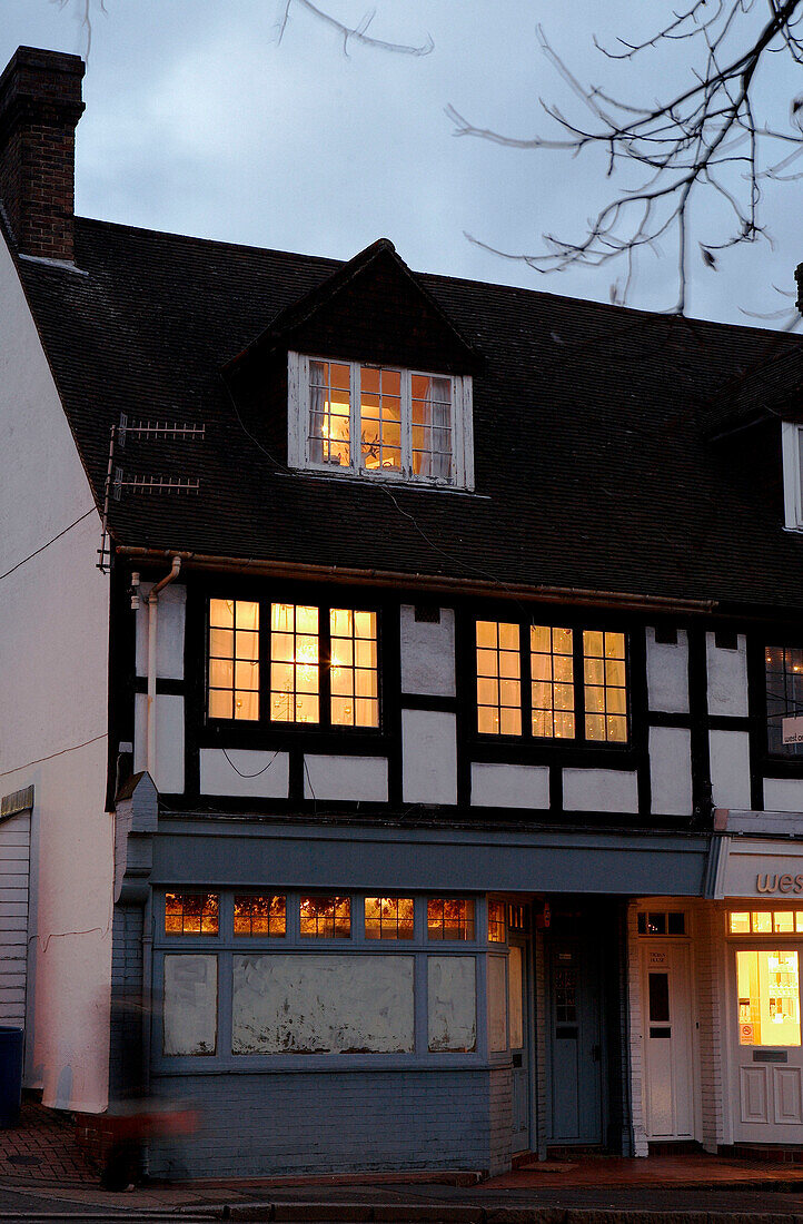 Lit windows of timber framed house at dusk