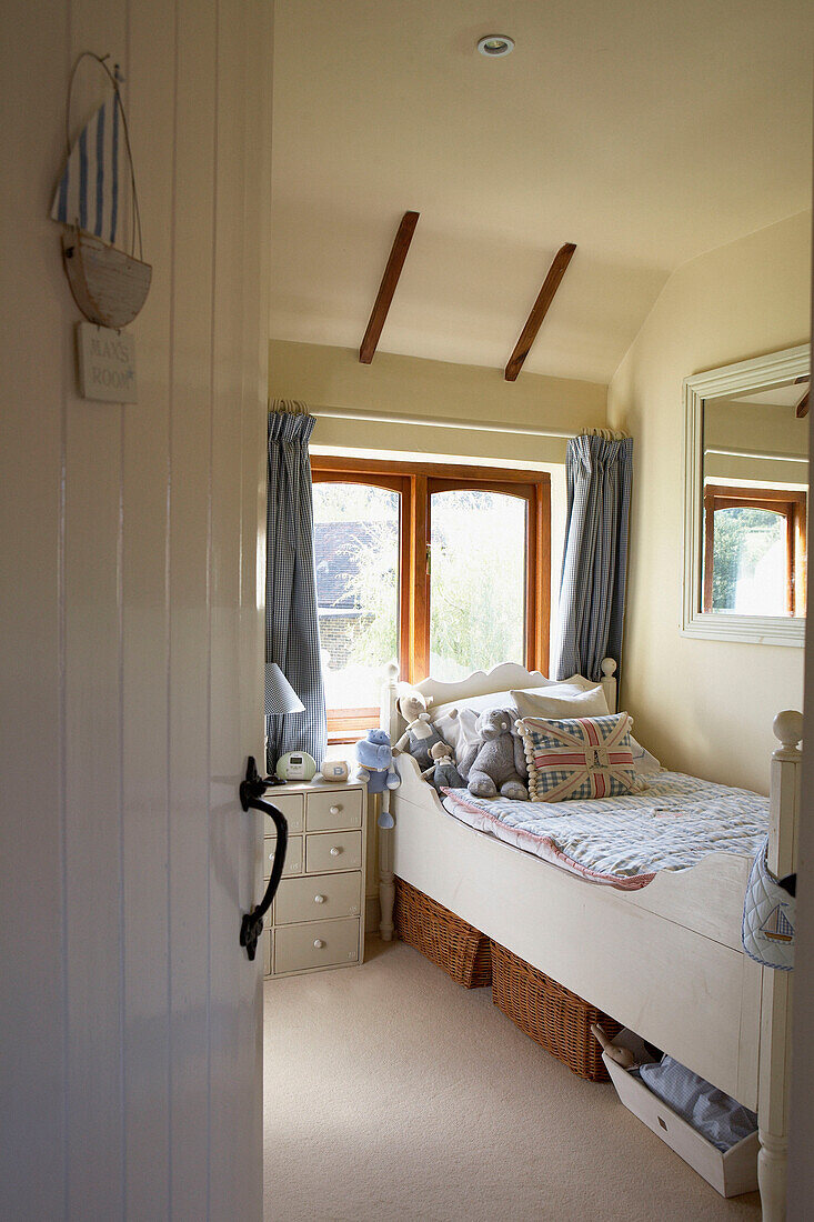 Single bed in child's room below sunlit window
