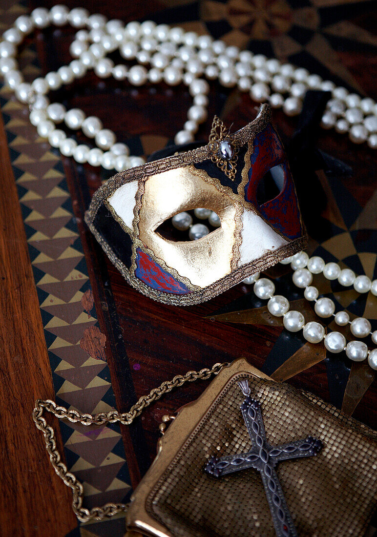 Venetian mask and string of pearls with gold lame handbag 