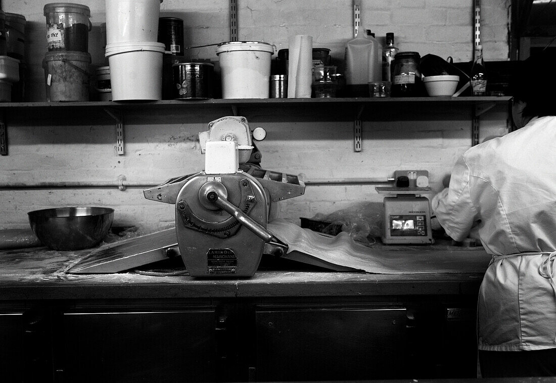 Koch steht an einer Arbeitsfläche mit Bäckereimaschinen